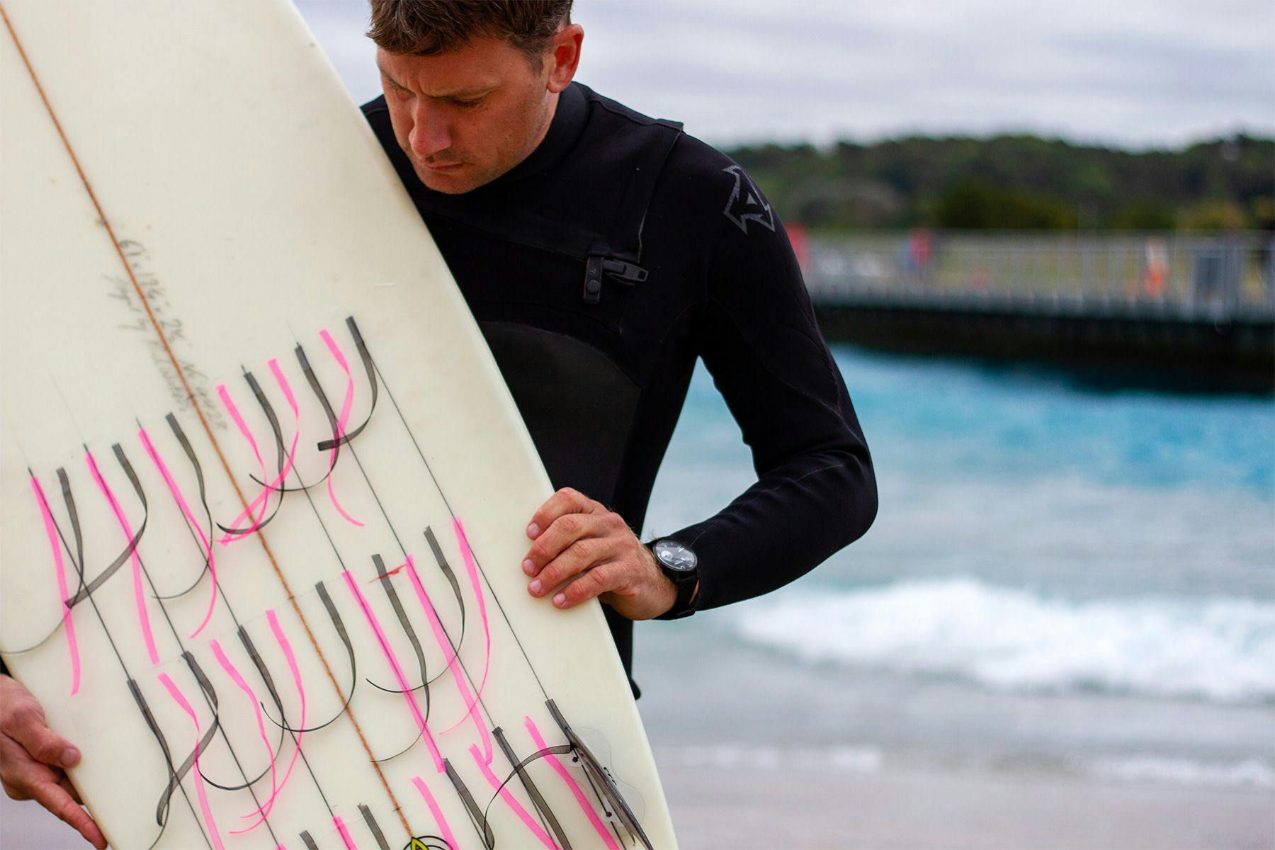 harry knight at the wave artificial wave pool in bristol with telltales stuck to the bottom of his surfboard to test the hydrodynamics of a surfboard