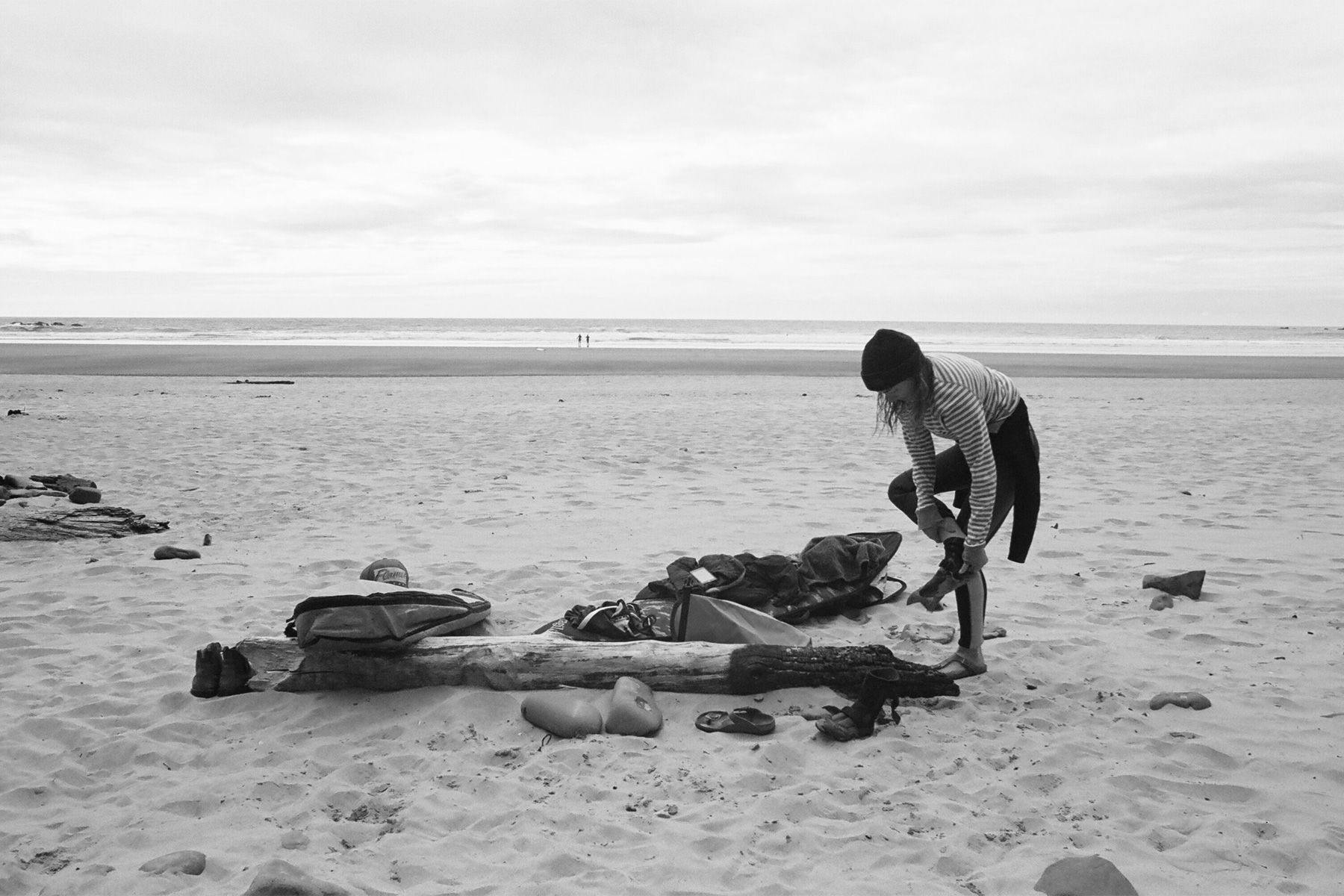 surfing changing out of their wetsuit on a beach in british columbia