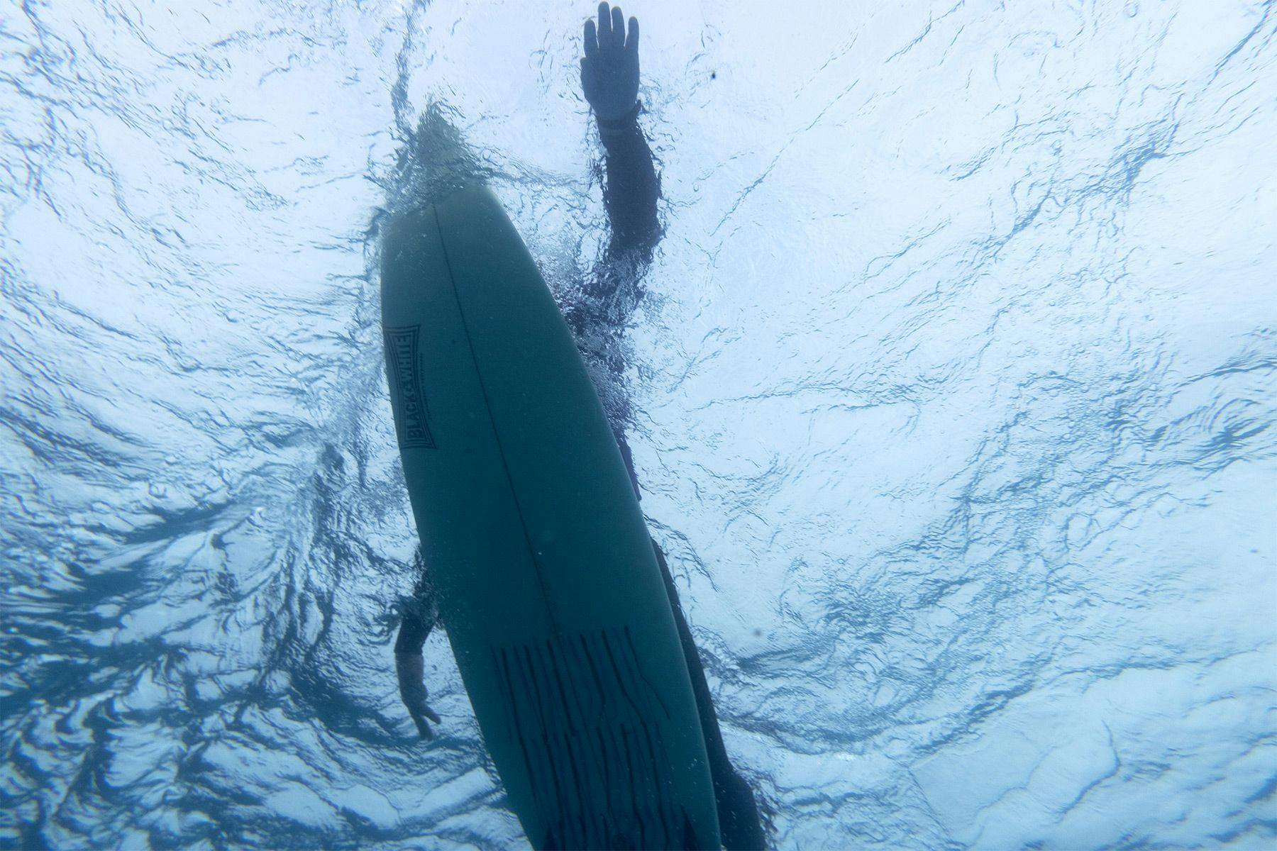 looking up at a surfer paddling from under the water