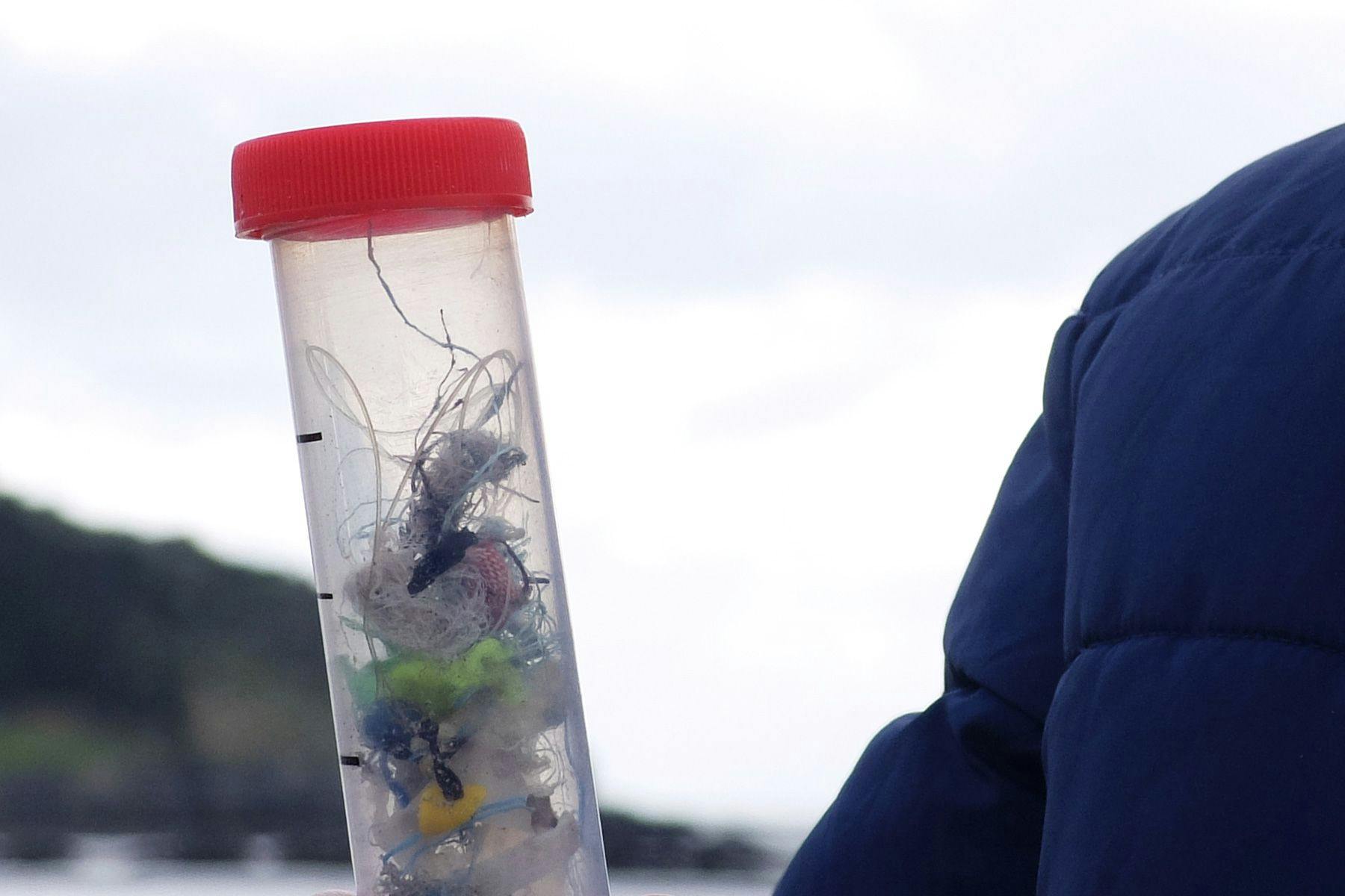 large test tube full of beach plastics