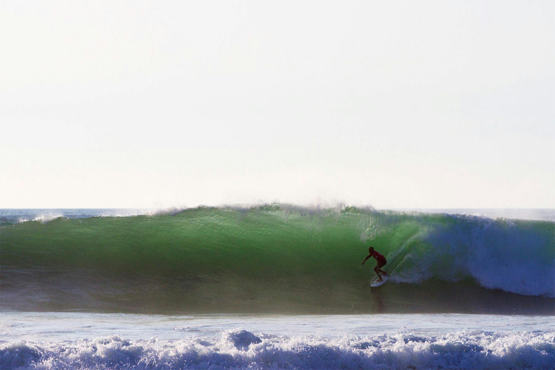 kelly slater surfing a backlit wave in a surf contest