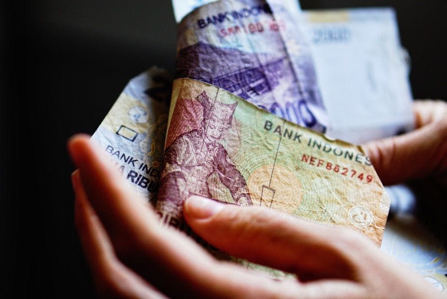 A 5000 Rupiah note with a Tanah Datar woman weaving a songket fabric.