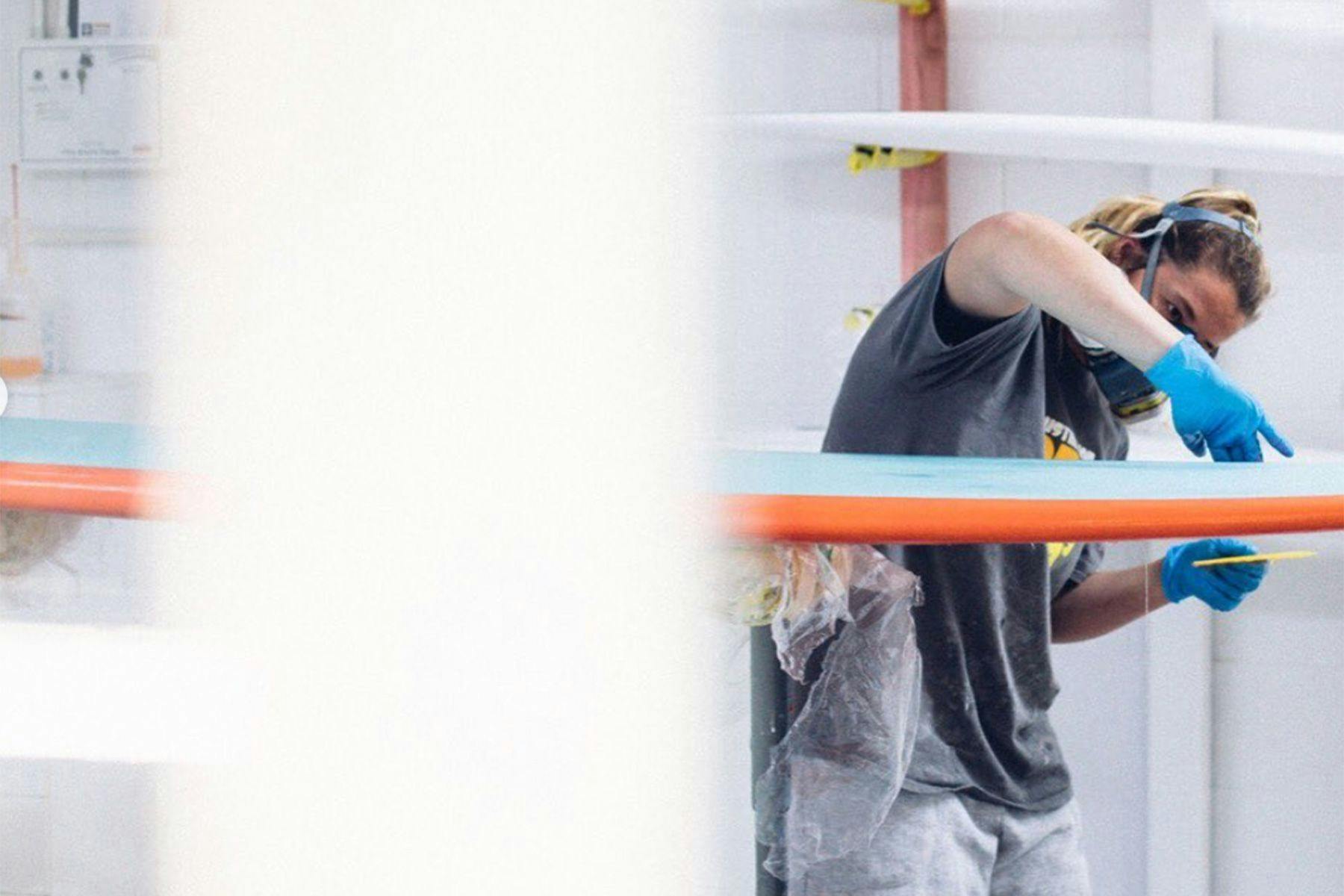 Lou Aitken glassing a surfboard in new zealand